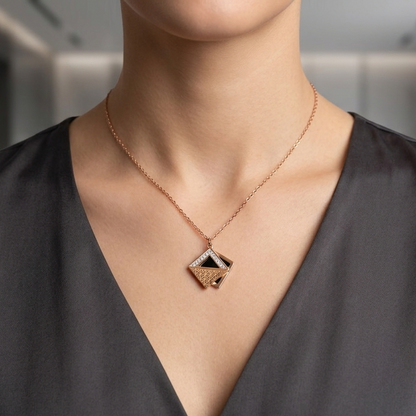 Person wearing a gold necklace with a diamond-shaped pendant in a blurred indoor setting