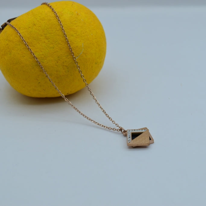 Gold necklace with a geometric pendant on a yellow sphere against a light gray background