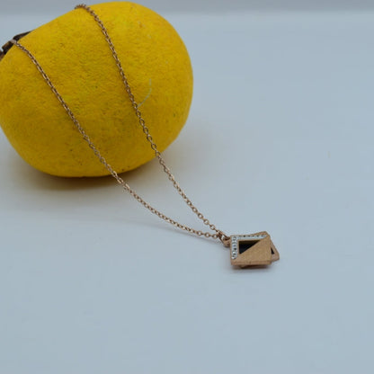 Gold necklace with a geometric pendant on a yellow sphere against a light gray background