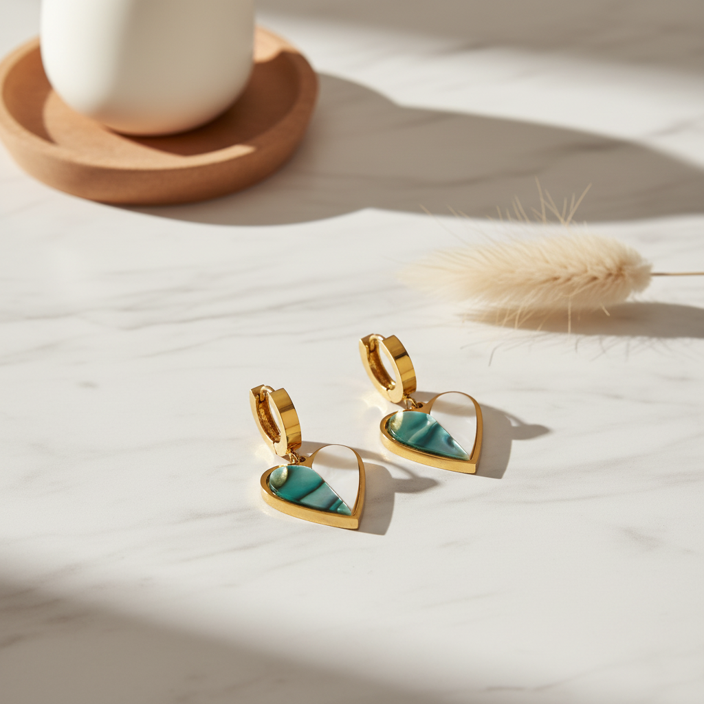 Heart-shaped earrings with gold frames and green and white stones on a light background