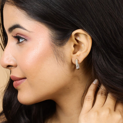Close-up of a woman wearing pearl earrings with a neutral background