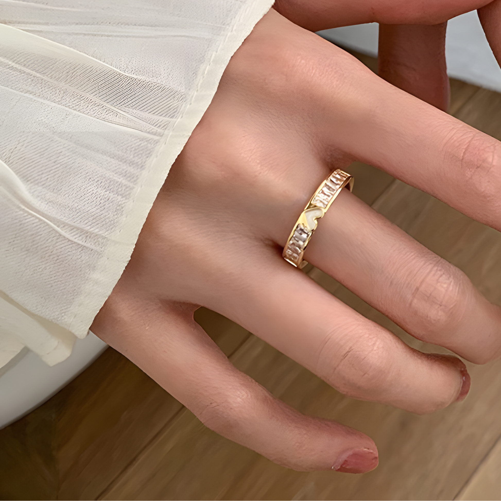 Close-up of hands wearing gold rings on a neutral background